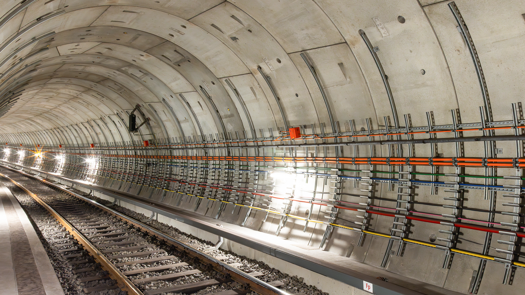 Innenansicht eines modernen U-Bahn-Tunnels mit Schienen, Kabelsystemen und Beleuchtung