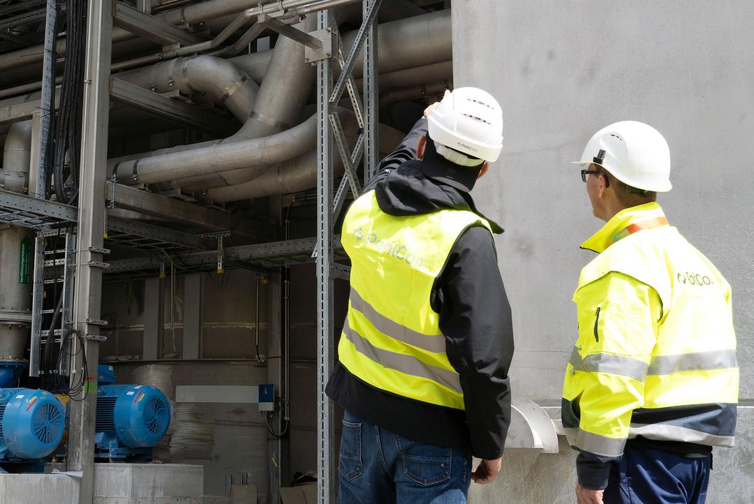 Zwei Monteure begutachten die Technische Gebäudeausrüstung eines Gebäudes