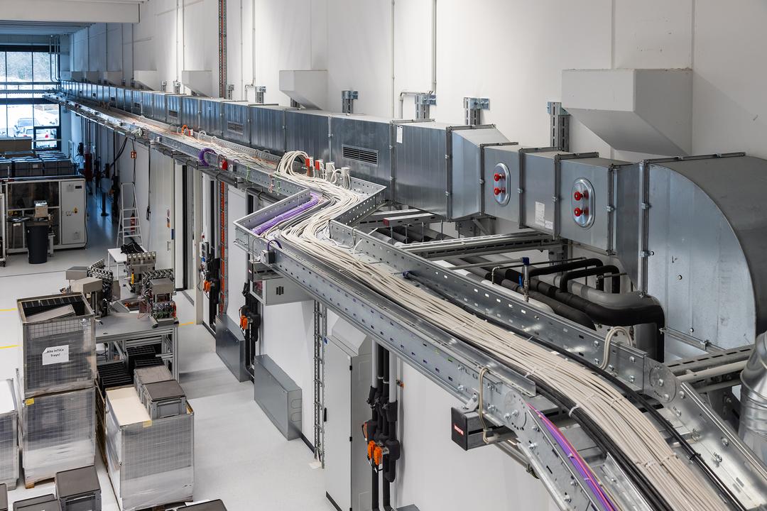 Moderne Produktionshalle mit Detailsicht auf Kabeltragsystem und Schacht an der Wand